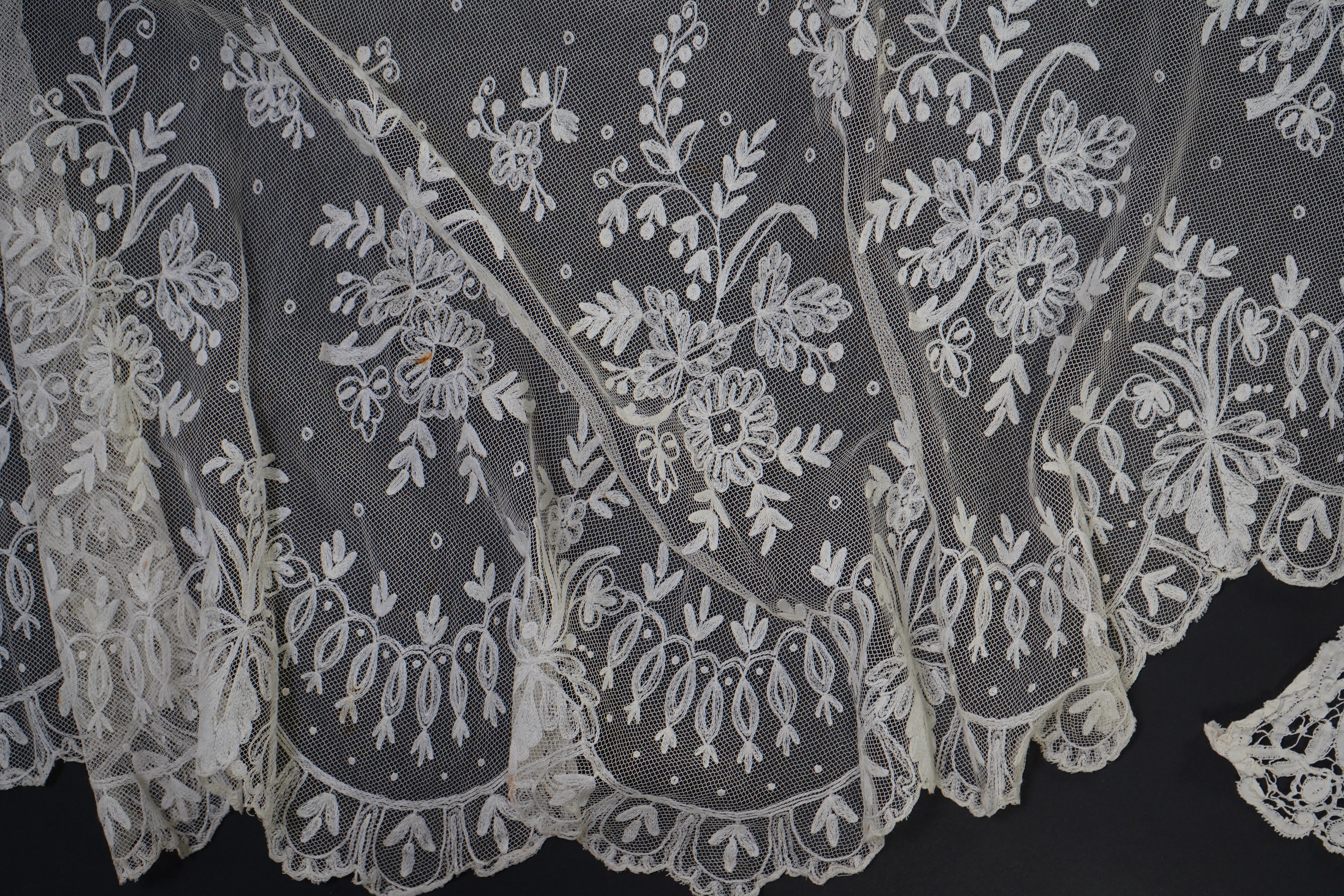 A white tape lace on net bed cover, a cream lace needle run panel, three Brussels bobbin lace collars, a lappet and two beaded tea pot covers, bed cover 200cm x 250cm. Condition - the bedcover has damage to the netting,